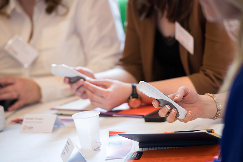 Members around a table using a clicker to vote