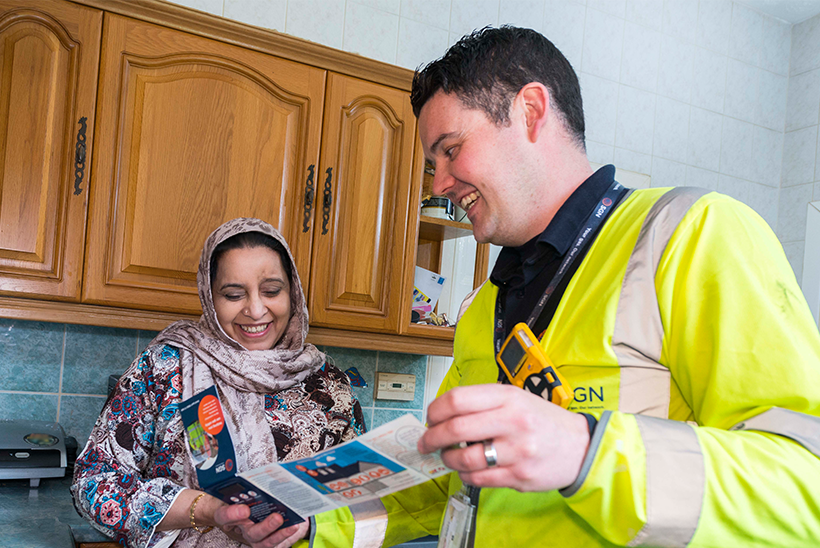 An engineer shows an SGN leaflet to a customer