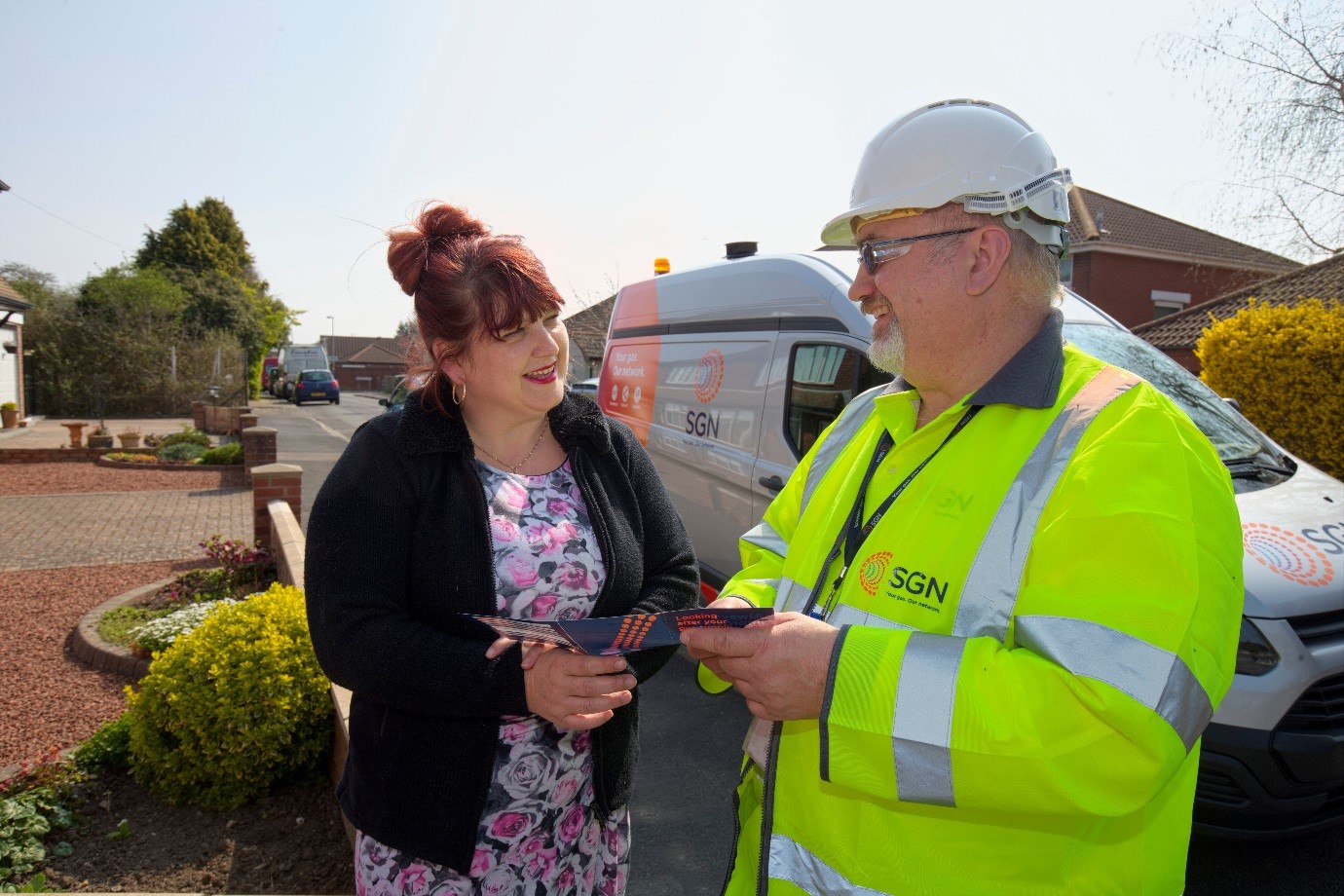 AN SGN gas engineer helps a customer in front of an SGN van.