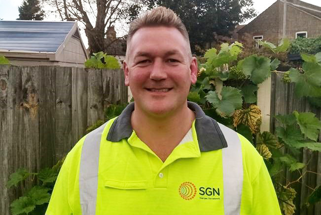 Gas engineer outdoors smiling at camera and wearing hi-vis clothing 