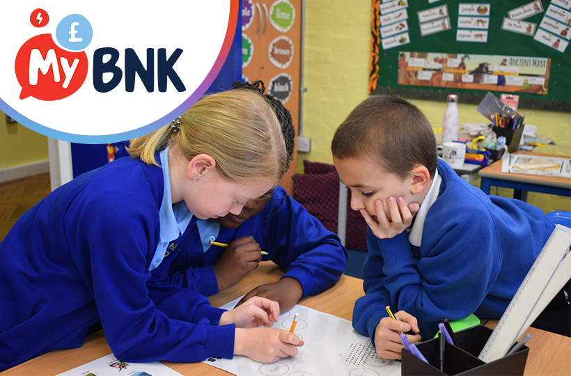 Three primary school aged children in a classroom working on MyBnk activity sheets