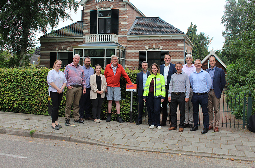 A home with a group of people standing outside posing for the camera