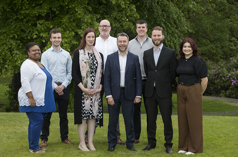 A group of people standing in a field wearing business attire.