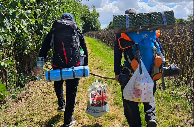 Two men walking with heavy packpacks loaded up