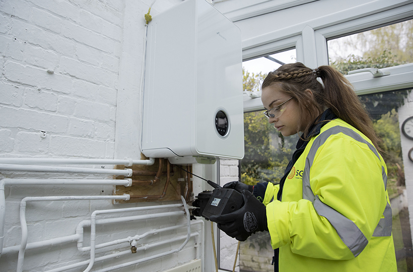 female SGN engineer working on a boiler in a customer home