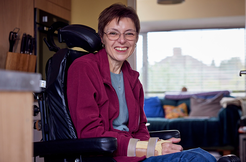 woman in a kitchen, sitting in a wheelchair and smiling