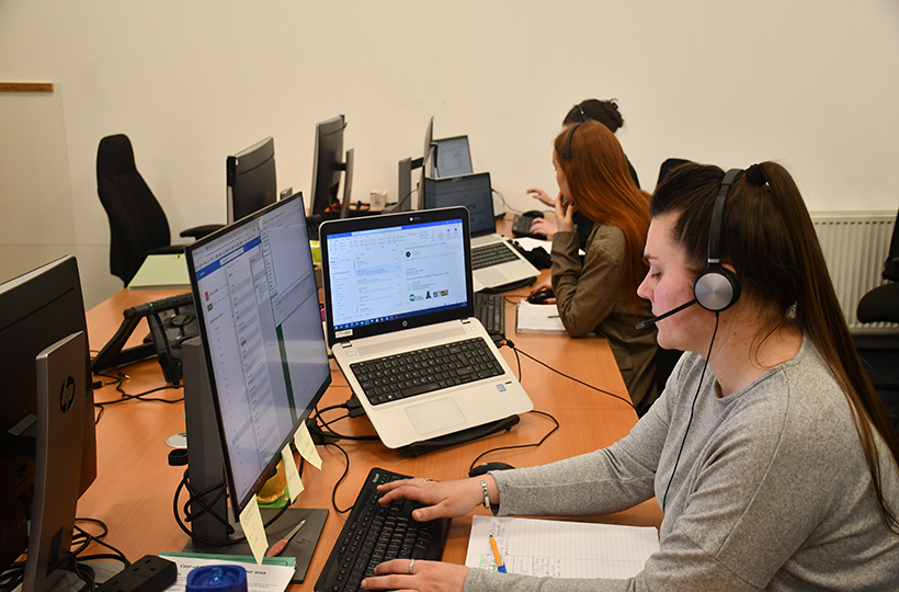 Female YES energy advisor sitting at a desk, working on a computer and wearing a headset