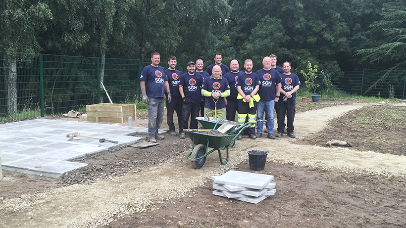 SGN team of volunteers pose for a picture at the site of landscape garden with equipment and new patio