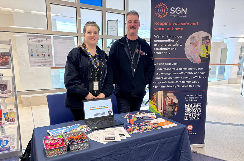 A man and woman standing behind a table next to an SGN banner