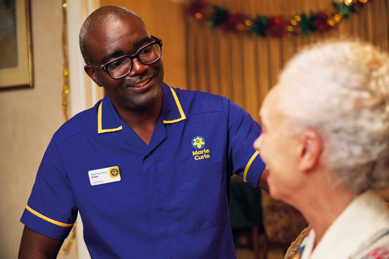 A carer in a Marie Curie uniform with a person with grey hair