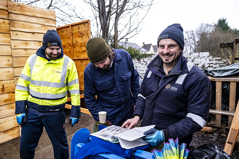 Three men standing around a sheet of instructions