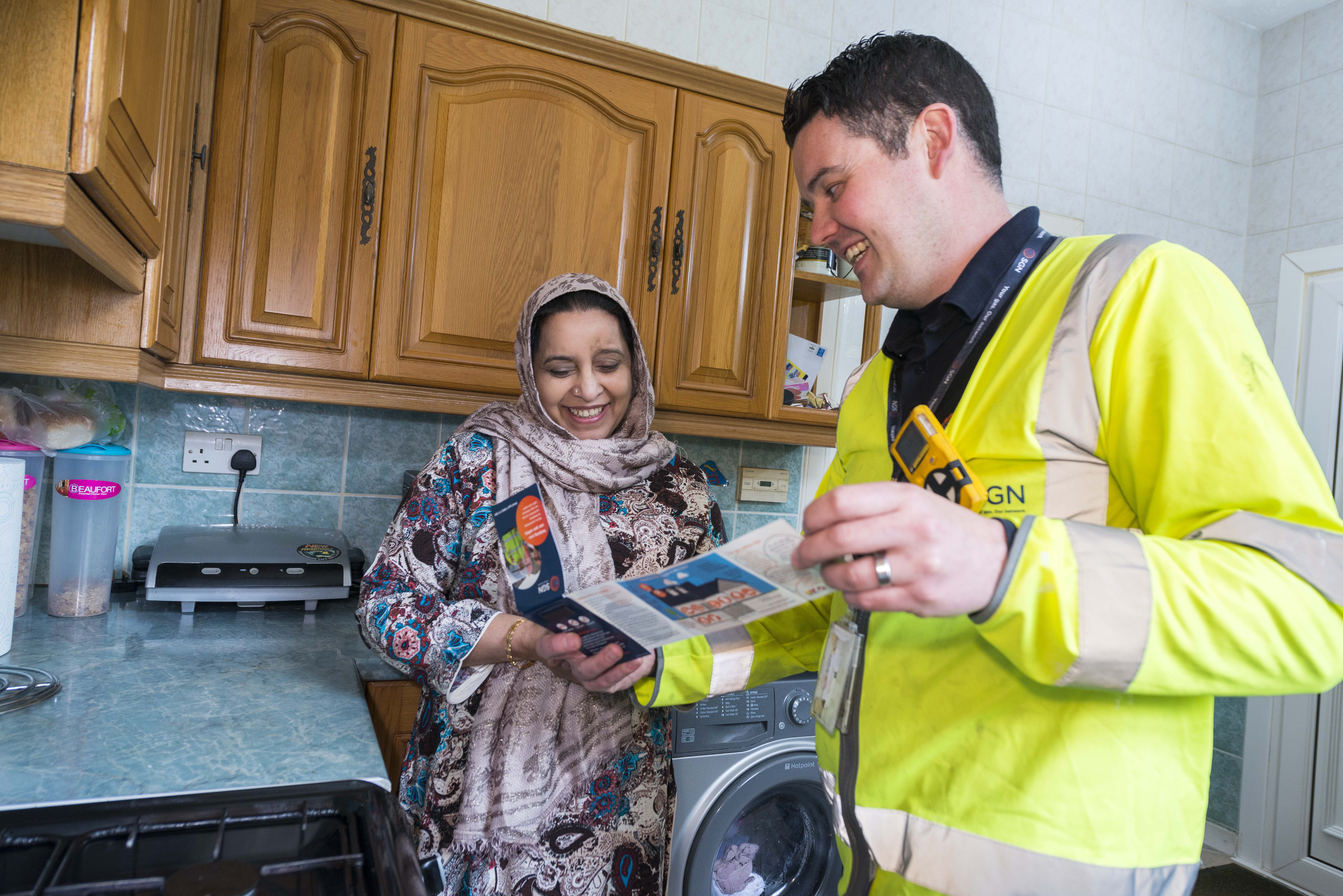 an SGN engineer talking to an older Muslim woman in her kitchen
