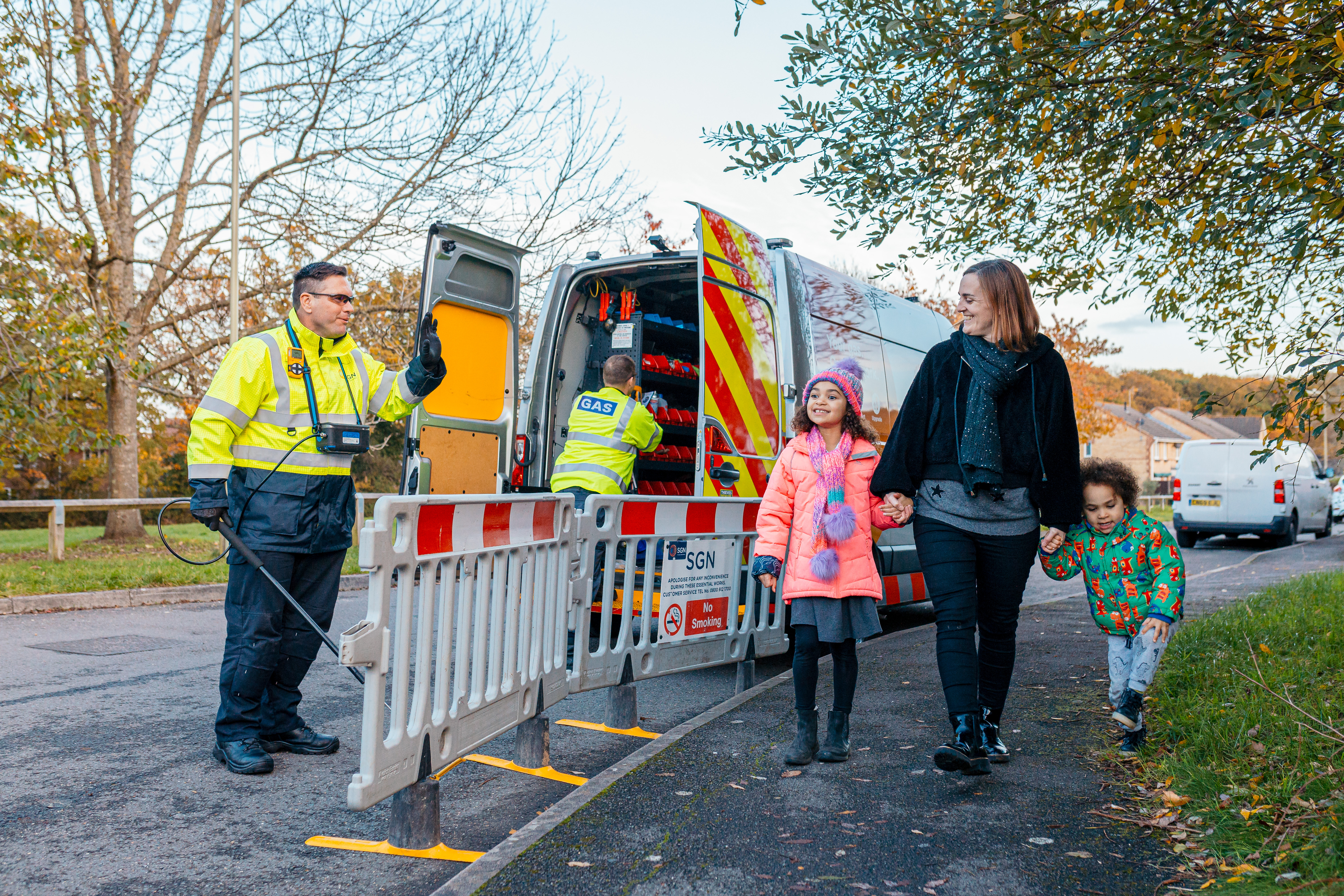 A young family walking past SGN engineers at a worksite