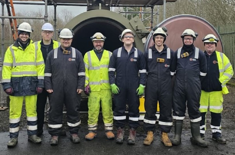 Eight men in a row wearing personal protective equipment