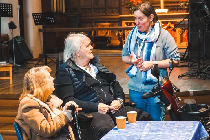 Residents are talking to a Warm Welcome volunteer at the Holy Trinity warm hub in Redhill