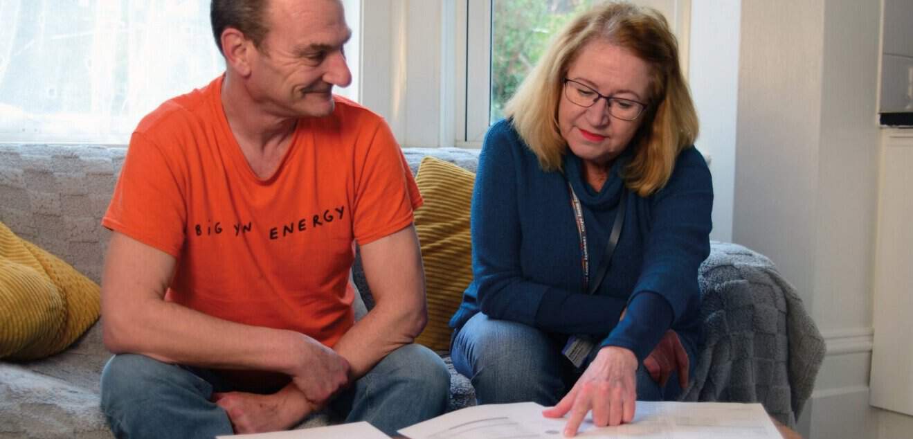 A resident is sitting with a Community Energy Pathways advisor receiving energy advice at a home visit