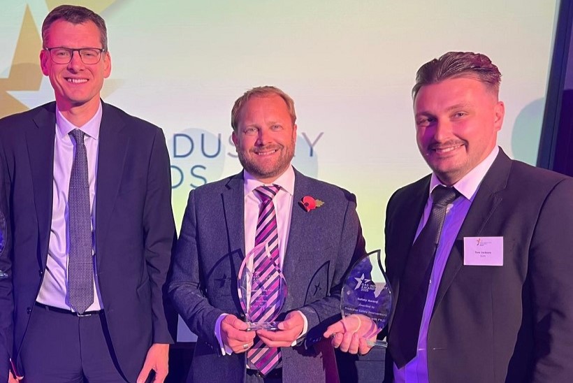 Three male colleagues from SGN standing in a row at the IGEM Awards ceremony 2025. Two are holding trophies