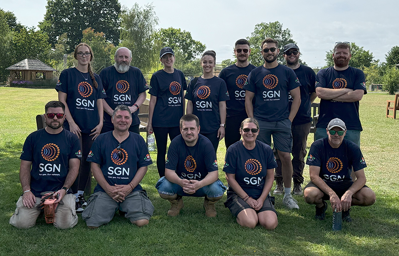 A group of smiling people stood in the sunshine