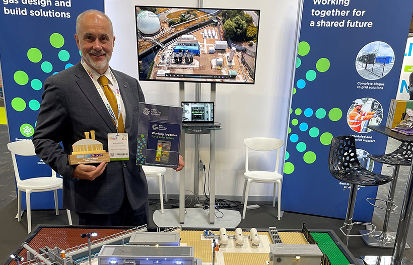 A man in a suit holding an award in front of our Lego model of the Deephams Gas to Grid plant