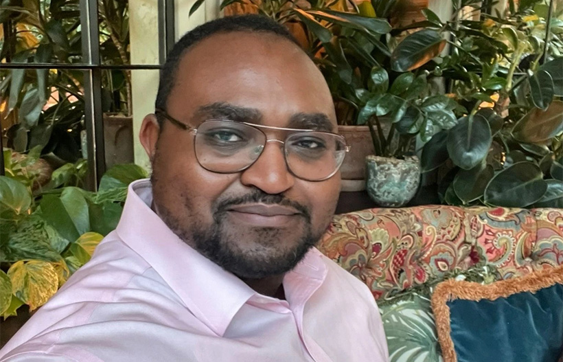 A Black man with glasses smiling at the camera