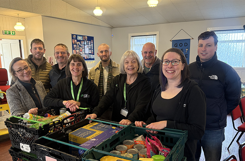 A group of people at a foodbank standing in front of baskets of food