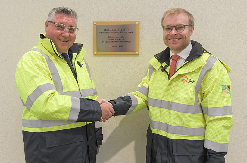 Two men shaking hands wearing PPE