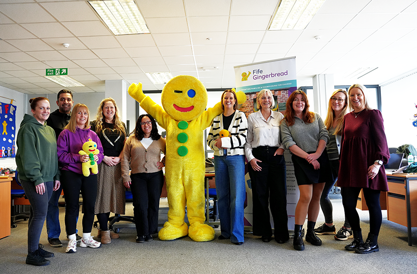 A group of people posing with a gingerbread man mascot