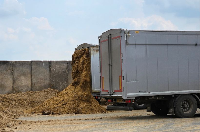 Image showing two lorries side by side, with feed being emptied from one of them