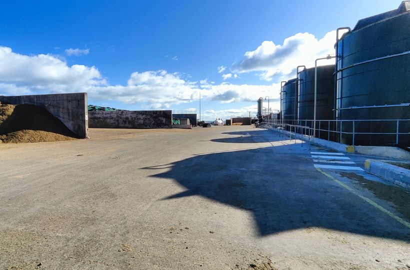 Image showing a farmyard with large pits of grain on the left and green silos on the right