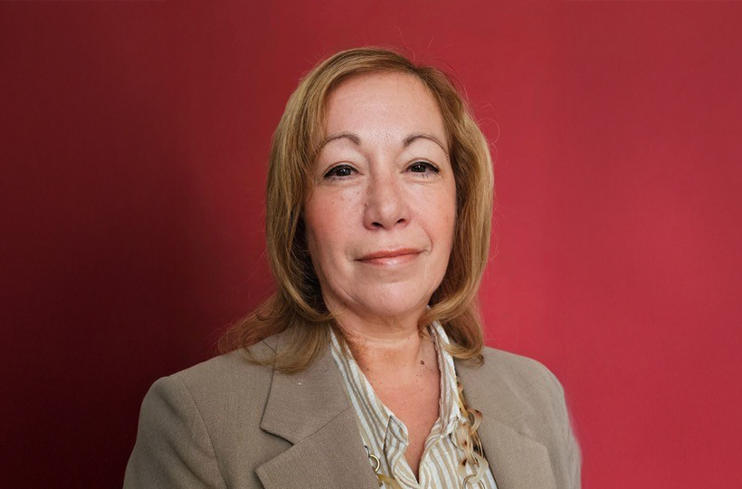 A woman with shoulder length blonde hair. She is wearing a shirt and suit jacket.