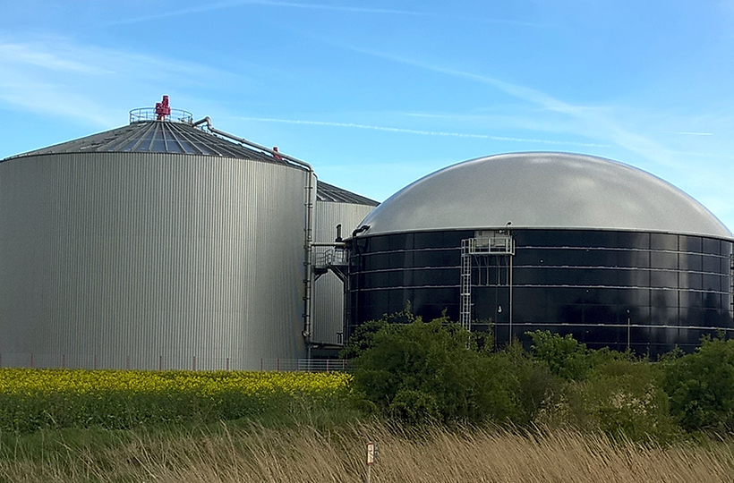 A biomethane plant with two large silos in the countryside.