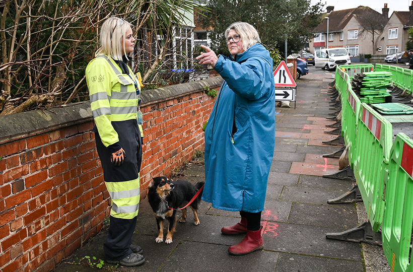A female engineer talking to an older customer on a street.