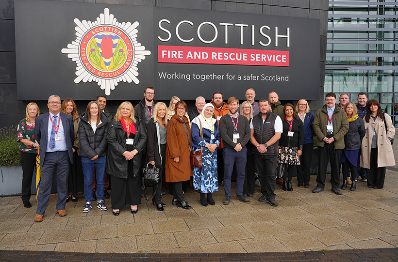 A large group of people standing outside a large Scottish Fire and Rescue Service building