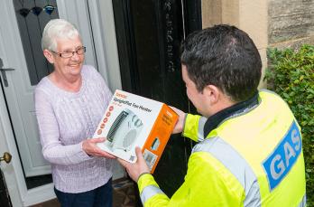 A SGN engineer handing a electric heater to a customer.