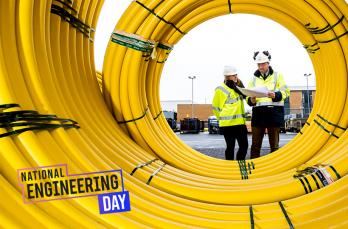 Two employees viewed through a coil of yellow pipe