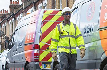 Gas engineer walking in road next to SGN vans