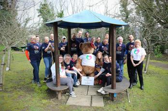 21 SGN volunteers with staff from The Elizabeth Foundation around a giant teddy bear