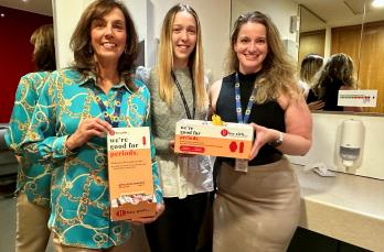 Three women holding boxes of Hey Girls period products