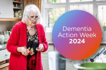 An older woman with grey hair in her kitchen. Text on circle: Dementia Action Week 2024
