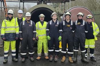 Eight men in a row wearing personal protective equipment