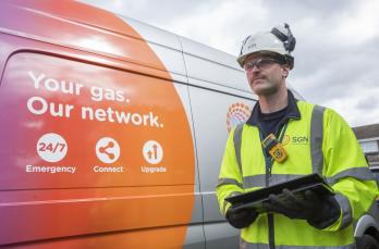 Engineer in PPE standing beside a van