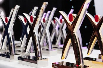 Multiple awards in silver and gold shaped like a person resembling an X