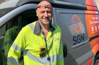 First Call Operative Paul Collins, who has used IncomeMax to support vulnerable customers, stands in front of an SGN van. He is wearing protective clothing.