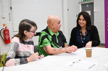 Janet, a female member of staff from SGN, sits next to two older people - one male and one female - to discuss dementia issues.