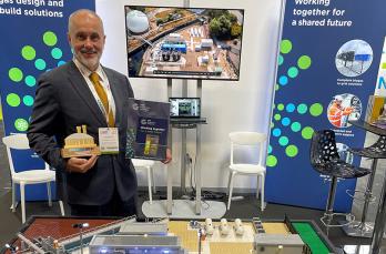 A man in a suit holding an award in front of our Lego model of the Deephams Gas to Grid plant