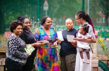 A group of smiling Black women looking at leaflets