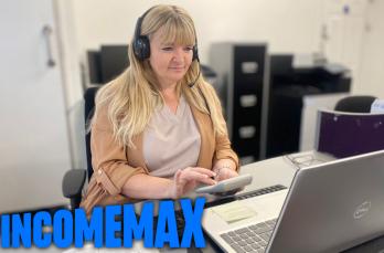 A woman wearing a headset using a calculator and laptop