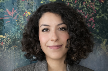 A woman smiling to camera with a floral background